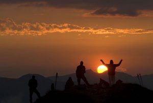 Sonnenaufgang auf der Bergspitze mit mehreren Wanderern